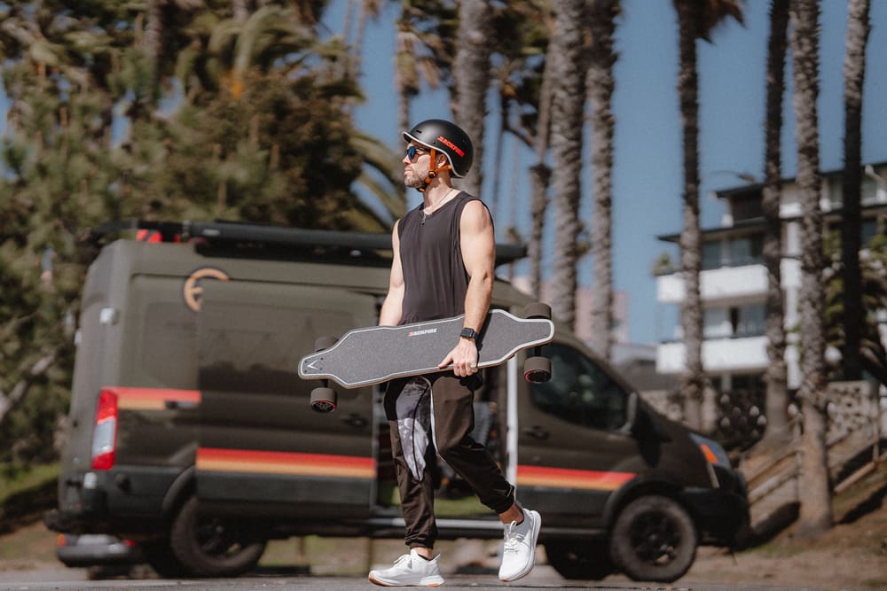 A man holding a skateboard while walking down the street.